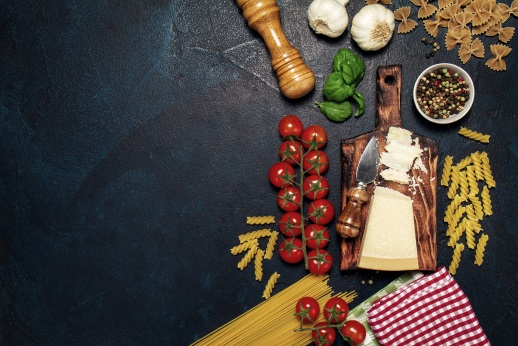 Italian food or ingredients background with fresh vegetables, pasta, cheese parmesan and spices. Top view, view from above. Copy space. Dark background.